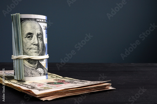 Rolled dollar banknotes on a desk with free space.