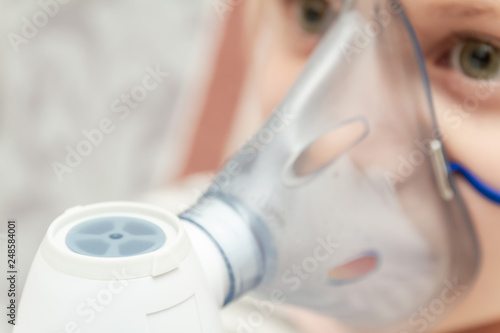 Little girl making inhalation with nebulizer at home. Little girl with inhaler. Closeup, selective focus