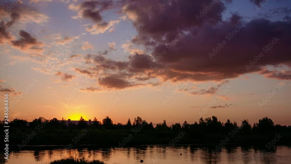 Sunset in summer on the river behind a horizon with a forest under a cloudy sky Sunset in summer on the river behind a horizon with a forest under a cloudy sky