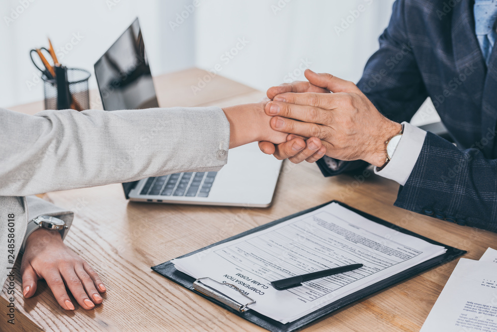 cropped view of businessman holding woman hand over table in office, compensation concept cropped view of businessman holding woman hand over table in office, compensation concept