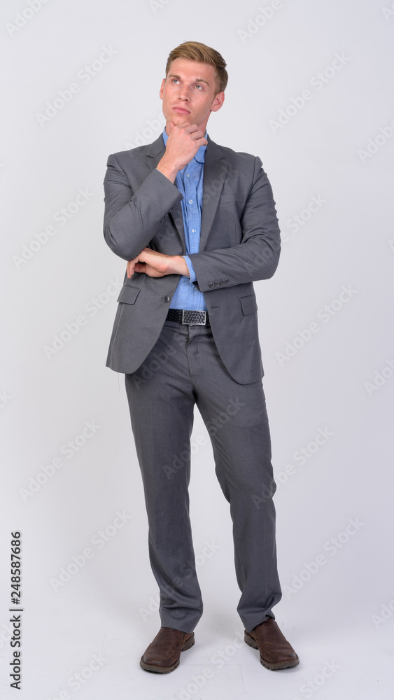 Full body shot of young handsome businessman with blond hair thinking Full body shot of young handsome businessman with blond hair thinking