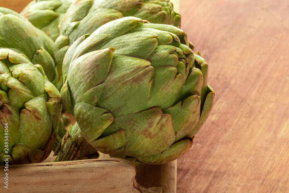 Obraz premium A closeup of a globe artichoke on a rustic wooden background with copy space