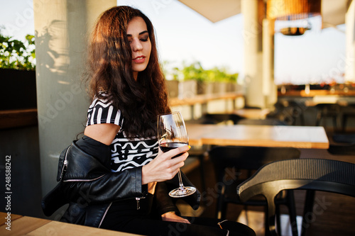 Young curly woman enjoying her wine in a bar.