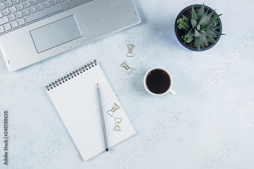 Office desk table with computer, supplies, notebook, flower and coffee cup. Top view with copy space, flat lay photo