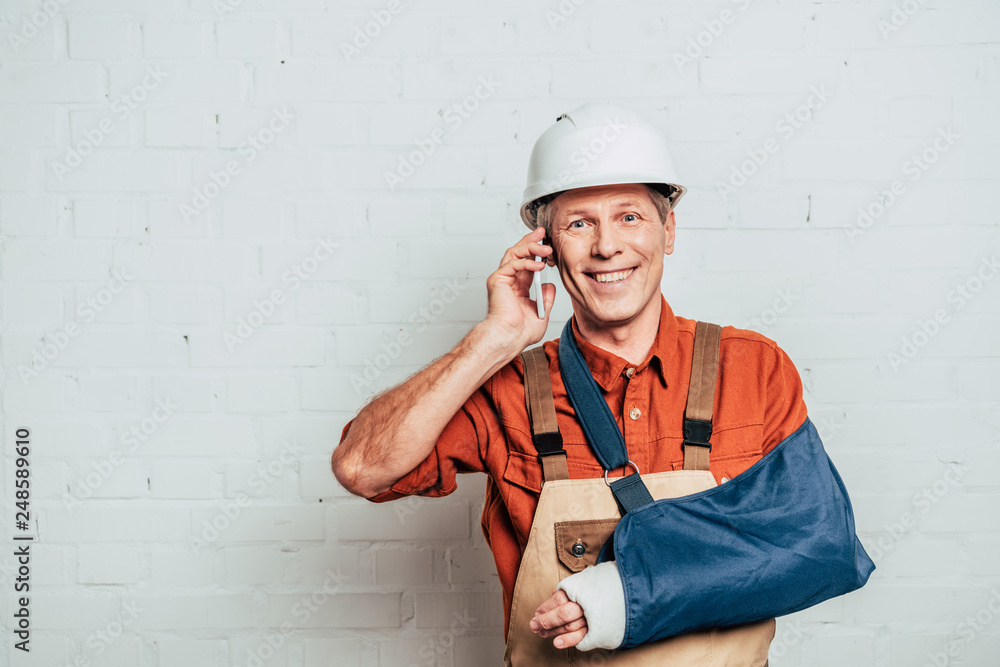 repairman with arm bandage talking on smartphone at white textured background repairman with arm bandage talking on smartphone at white textured background