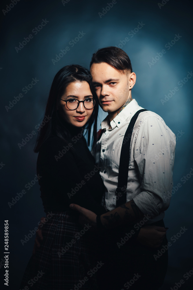 Couple in fashionable clothes on a dark smoky background Couple in fashionable clothes on a dark smoky background