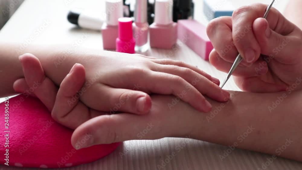 young mother helps her daughter paint her nails with varnish, treats her nails with a nail file young mother helps her daughter paint her nails with varnish, treats her nails with a nail file