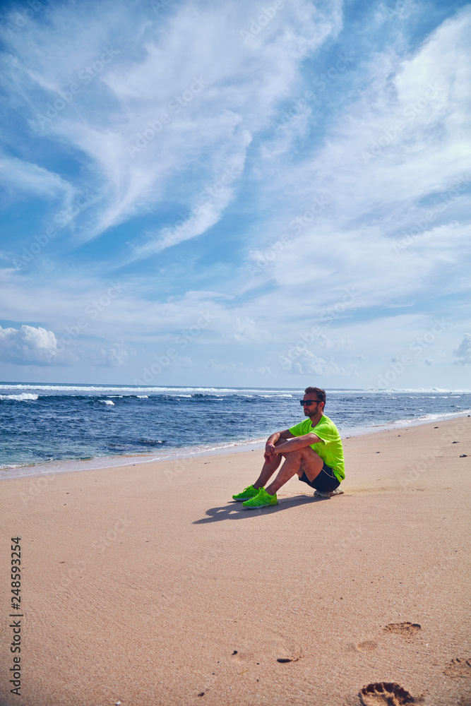 Sportsman stretching on a exotic tropical beach after jogging / exercising.