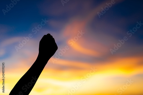 Silhouette fist fo the woman show success and beautiful sky in sunset.