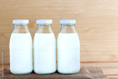 Three bottles of milk on a wooden table. Copy space for text or image.