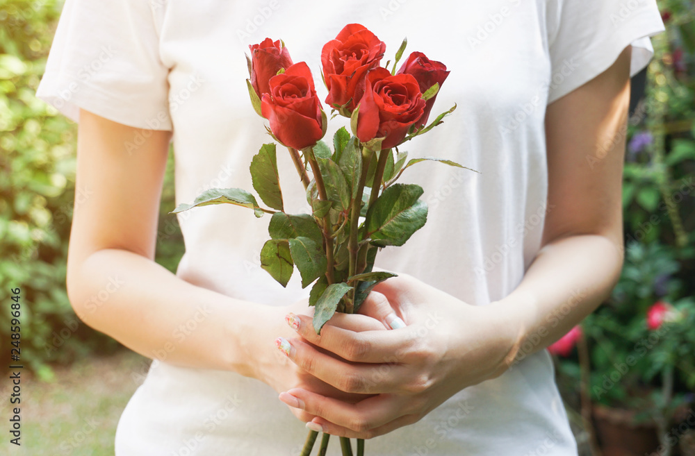 Woman holding red roses in the garden.