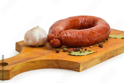 Bologna sausage among various spices on a wooden cutting board photo