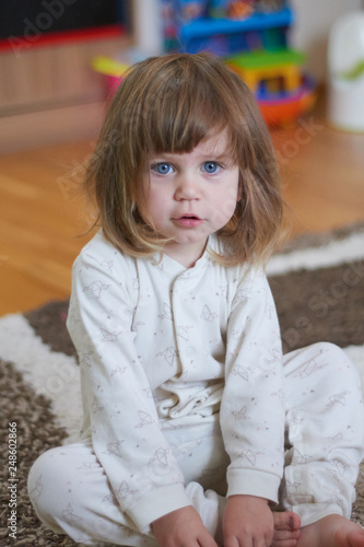 Portret of adorable baby girl with blue eyes and funny curly hair posing in her room