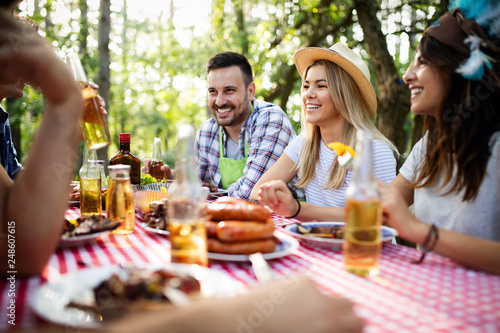 Group of happy friends eating and drinking beers at barbecue dinner