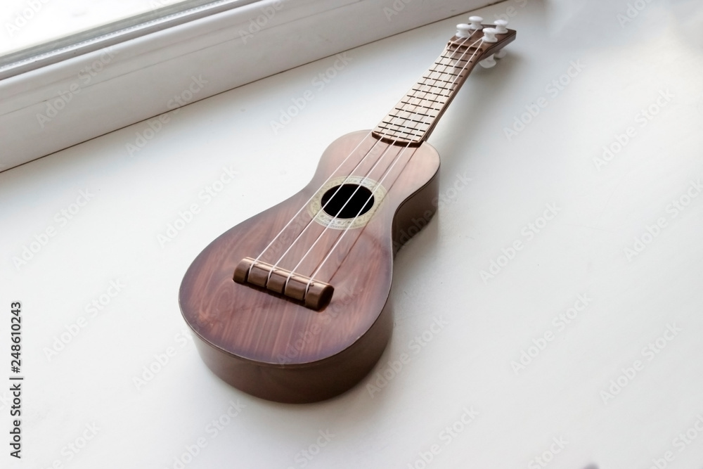 Fototapeta premium a wooden brown toy guitar is lying on the window