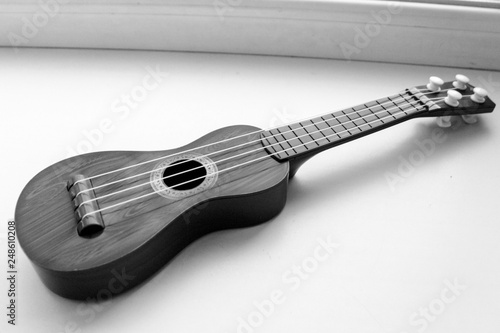 a wooden brown toy guitar is lying on the window photo