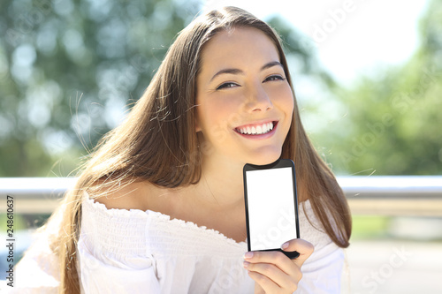 Happy woman showing blank phone screen outside