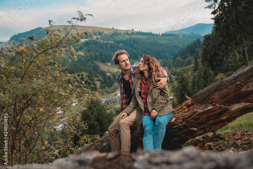 Happy couple hugging and sit on the Carpathians forest. Romantic trip to the mountains. Happy honeymoon vacation in wild wood