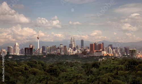 Unfiltered realistic aerial sky view of Kuala Lumpur skyline buildings at a distance  with trees and nature