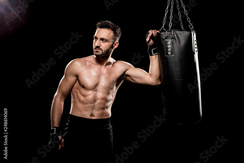 shortless boxer standing near boxing bag isolated on black