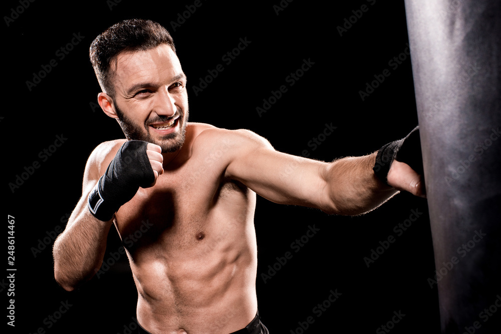 shortless sportsman kicking punching bag isolated on black