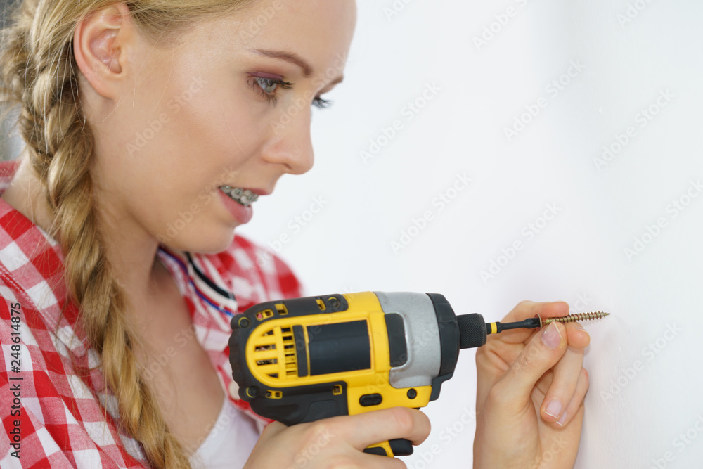 Woman drilling in wall Woman drilling in wall
