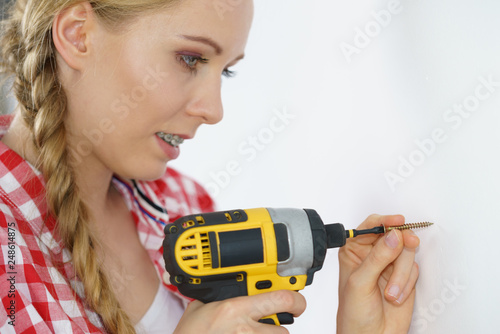 Woman drilling in wall