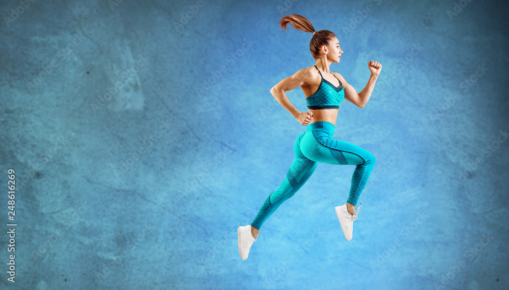 Young woman runner in turquoise sportswear jump in the air.