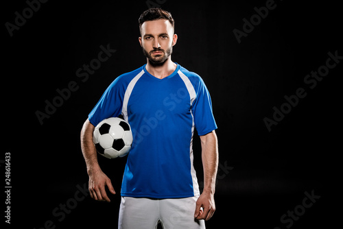 bearded football player standing with ball isolated on black © LIGHTFIELD STUDIOS