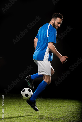 bearded sportsman in uniform playing with ball isolated on black © LIGHTFIELD STUDIOS