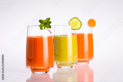 three glass of colorful organic vegan vegetable juice on a white background