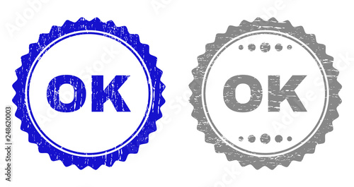 Grunge OK stamp seals isolated on a white background. Rosette seals with grunge texture in blue and grey colors. Vector rubber stamp imprint of OK text inside round rosette.