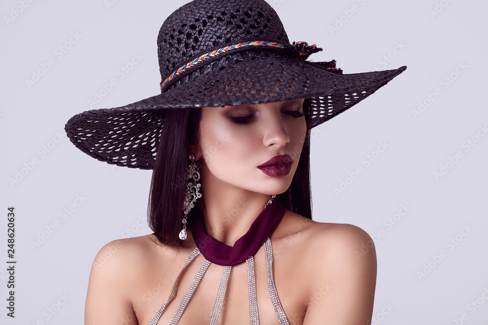 Elegant beautiful brunette woman in a colorful dress and wide hat Elegant beautiful brunette woman in a colorful dress and wide hat
