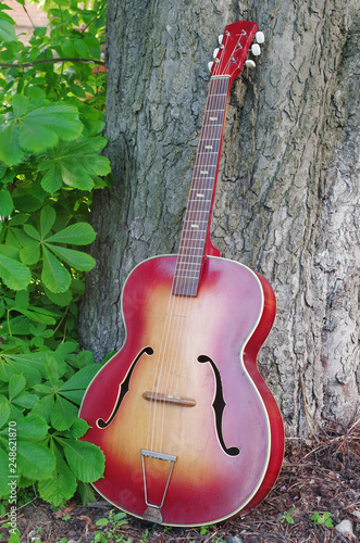Acoustic old guitar on a chestnut wood background