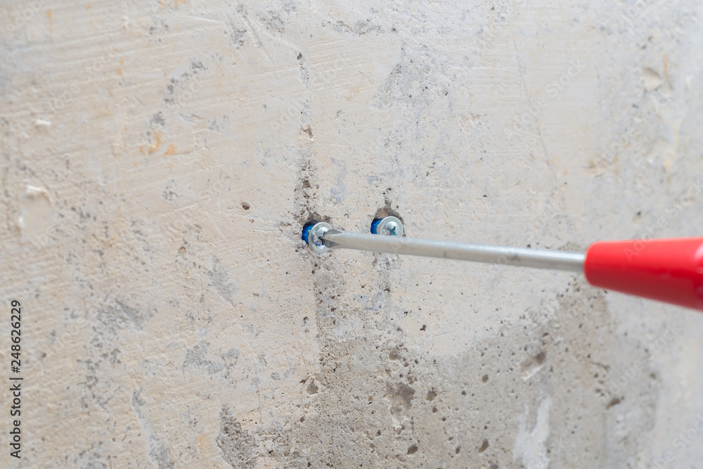 red screwdriver twists the screw into the wall red screwdriver twists the screw into the wall