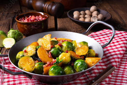 Brussels sprouts potato pan with bacon in rustic style