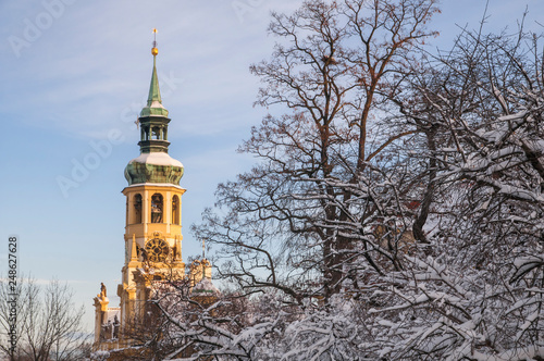 Prague Loreta Belltower among snowy trees