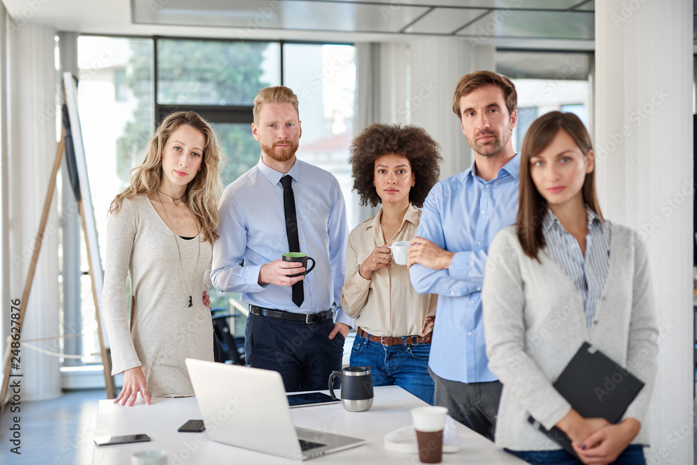 Small group of business people standing and posing at office. Start up business concept. Multi ethnic goroup. Small group of business people standing and posing at office. Start up business concept. Multi ethnic goroup.