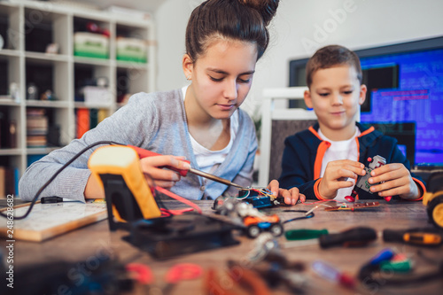 Happy smiling boy and girl constructs technical toy and make robot. Technical toy on table full of details