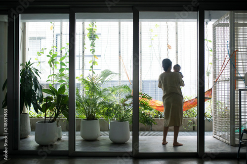 Mother standing on terrace and holding her baby. photo