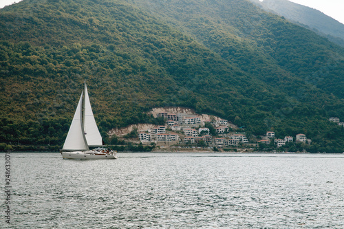 Sailboat flowing on the sea, on background Montenegro landscape.