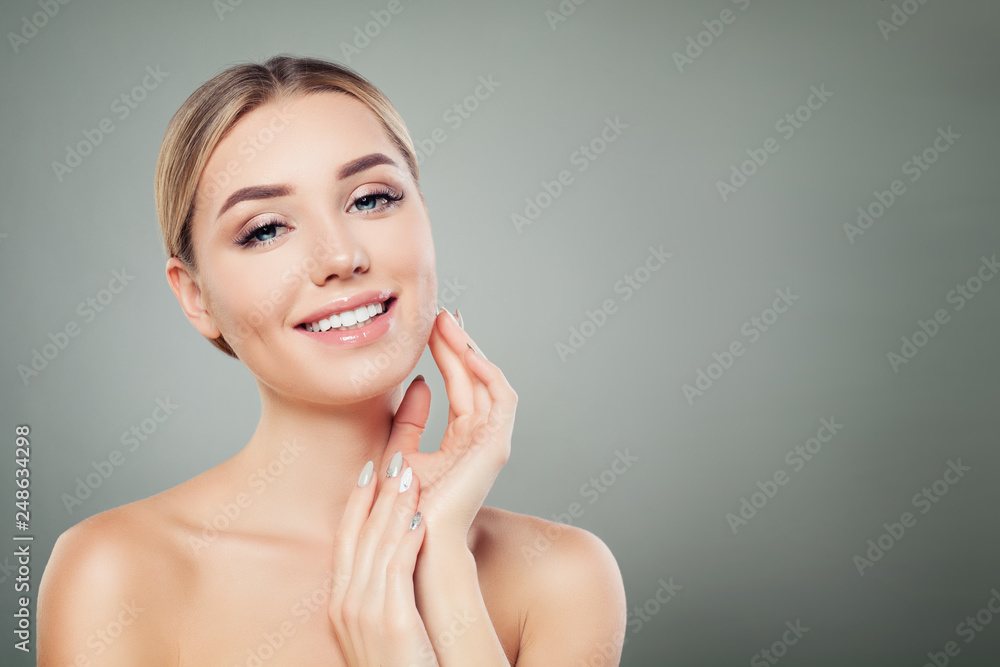 Beautiful woman smiling and touching her hand her face. Cute girl with clear skin. Facial treatment, face lifting and cosmetology concept