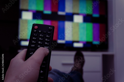 Female holding TV remote control in front of TV. Couch potatoe. Point of view shot.