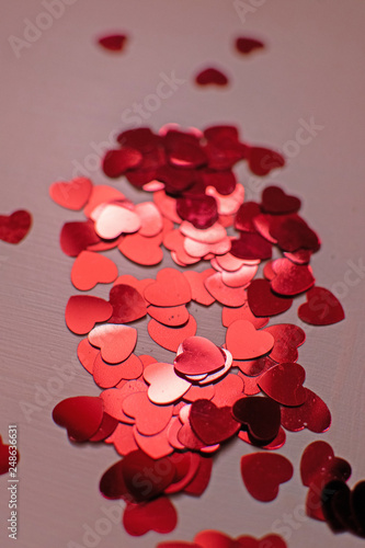 Red hearts. Heart confetti on coral background, glitter background. Color of the year 2019 - living coral.