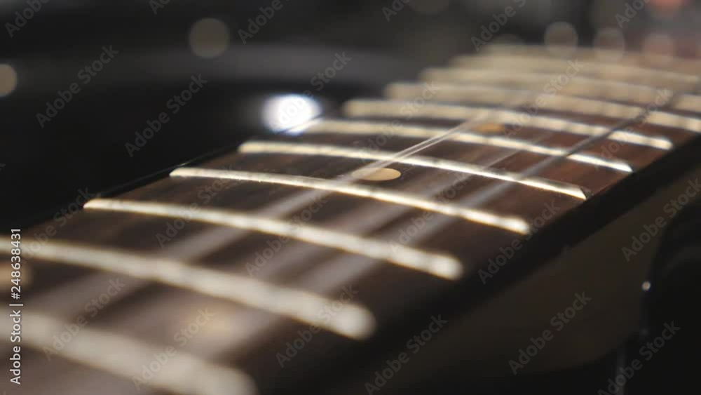 Close up of trembling guitar strings against fret. Chords being strummed and vibrating during playing. Beautiful background with wooden texture. Music performance. Blurred motion. Top view Slow motion Close up of trembling guitar strings against fret. Chords being strummed and vibrating during playing. Beautiful background with wooden texture. Music performance. Blurred motion. Top view Slow motion