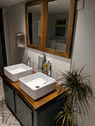 Two shiny  contemporary  ceramic wash hand basins installed on a pedestal cupboard  in perspective  in the gentlemen s toilets at a restaurant  bar