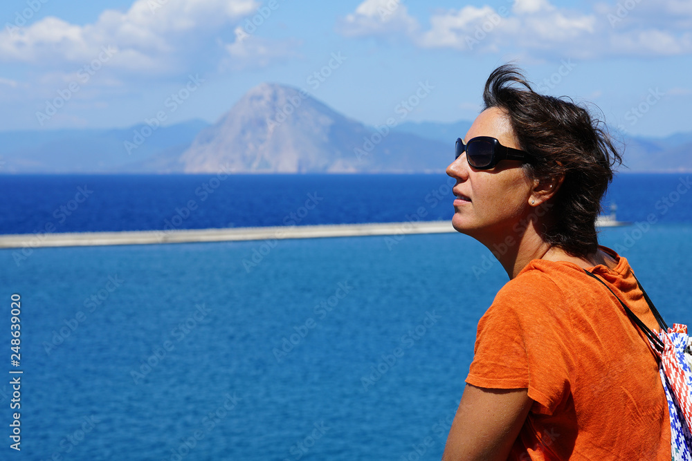 A tourist admires the landscape from the ferry that takes her on vacation in Greece A tourist admires the landscape from the ferry that takes her on vacation in Greece