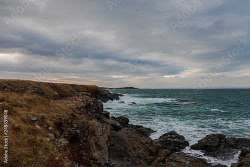 sea ​​scenery in dramatic weather in the blue hour. a landscape with dramatic clouds and stormy water that breaks down on the shore and the rocks.