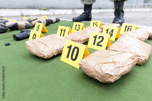 Police officer standing guard over seized packages of drug