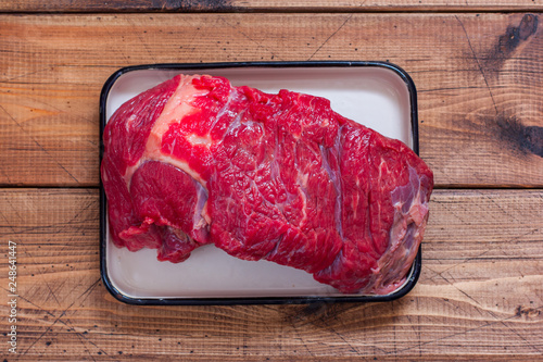 Raw beef for roasting with garlic on a wooden table, top view photo